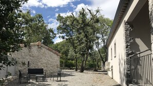 Un patio con un muro de piedra, un banco y un edificio con una reja de metal.