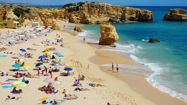 A beach with numerous umbrellas and people sunbathing. - Bright Apartment | Kitchenette + Air-Conditioning (Albufeira)