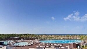 A resort with multiple swimming pools, sun loungers, and umbrellas, surrounded by palm trees and a view of the ocean. - Bright Apartment | Kitchenette + Air-Conditioning (Albufeira)