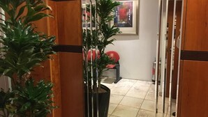 A hallway with wooden paneling, a potted plant, and a red chair. - Penta Hotel (Douglas)