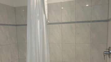 A bathroom with a shower curtain, a bathtub, and tiled walls.