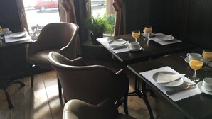 A dining area with tables set for breakfast, including plates, cups, and glasses of orange juice. - Penta Hotel (Douglas)