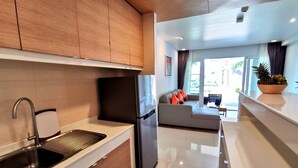 A modern kitchen with wooden cabinets, a stainless steel sink, and a black refrigerator. - Apartment with private jacuzzi and pool access. Just 800 meters to the beach. (Phuket)