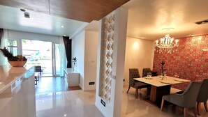 A modern dining area with a chandelier, a table set for two, and a decorative wall. - Apartment with private jacuzzi and pool access. Just 800 meters to the beach. (Phuket)