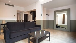 A modern living room with a dark grey sofa, a wooden coffee table with three potted plants, and a large mirror on the wall. - Quiet and charming apartment in Gracia neighborhood (Barcelona)