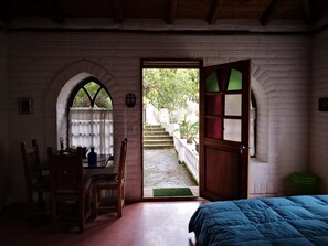 Experience the rustic charm of this inviting room, featuring a comfortable bed, wooden table, and serene garden views.