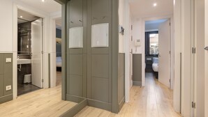 Habitación de hotel moderna con un amplio ventanal corredero, baño a la vista y un pasillo que conduce a otra habitación.