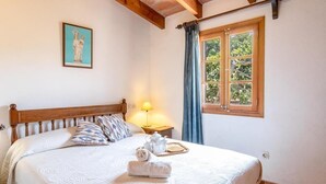 Un lit bien fait, avec une couette blanche, des oreillers et un ensemble de serviettes.