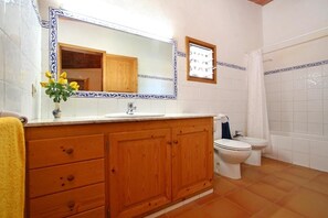 A bathroom with a wooden vanity, a sink, a mirror, a toilet, and a shower.