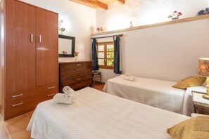 A bedroom with two beds, wooden wardrobe, dresser, and a window with curtains.