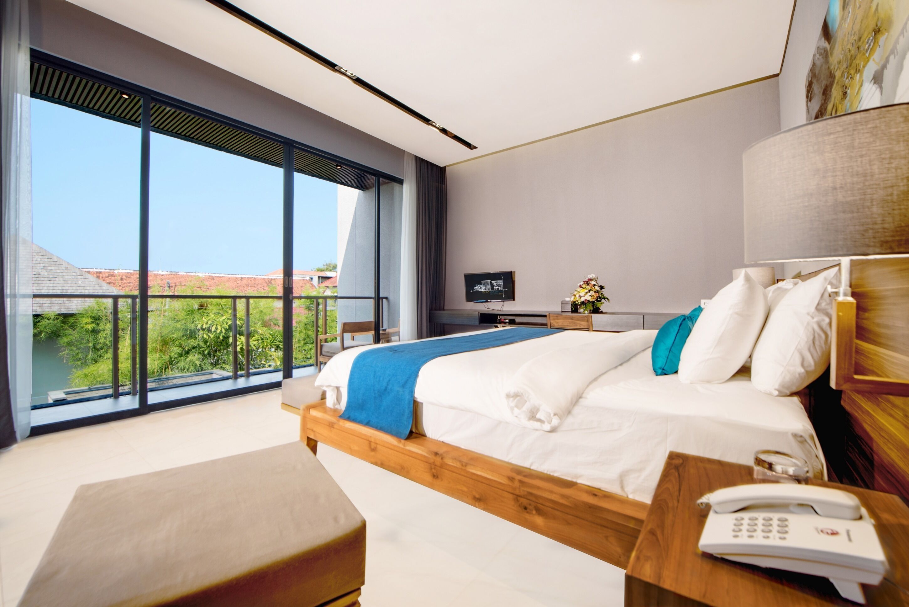 Een moderne hotelkamer met een groot bed, een houten hoofdbord, een nachtkastje met een telefoon en uitzicht op groen.