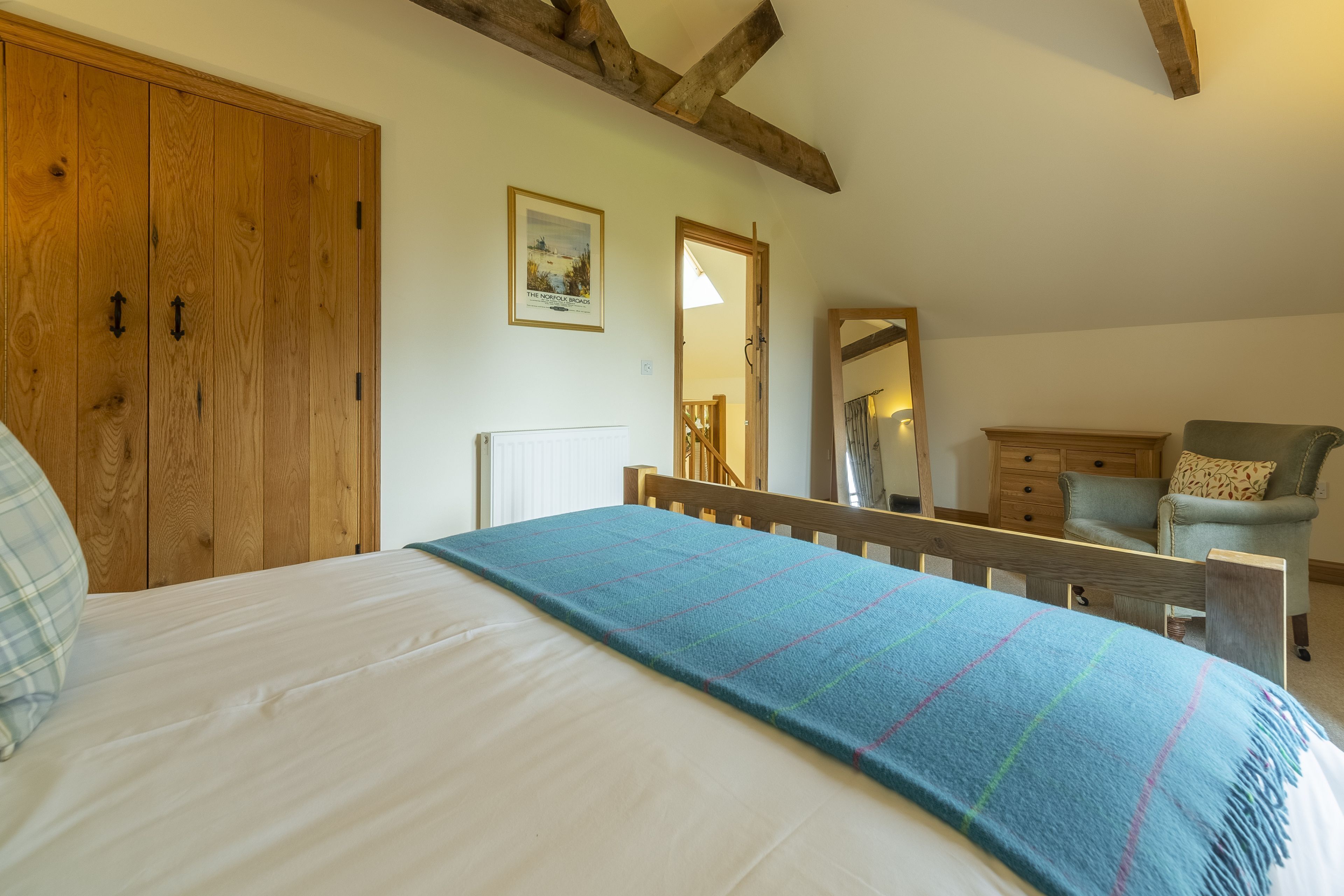 Une chambre à coucher avec un grand lit, une armoire en bois, un miroir, une chaise et une commode.