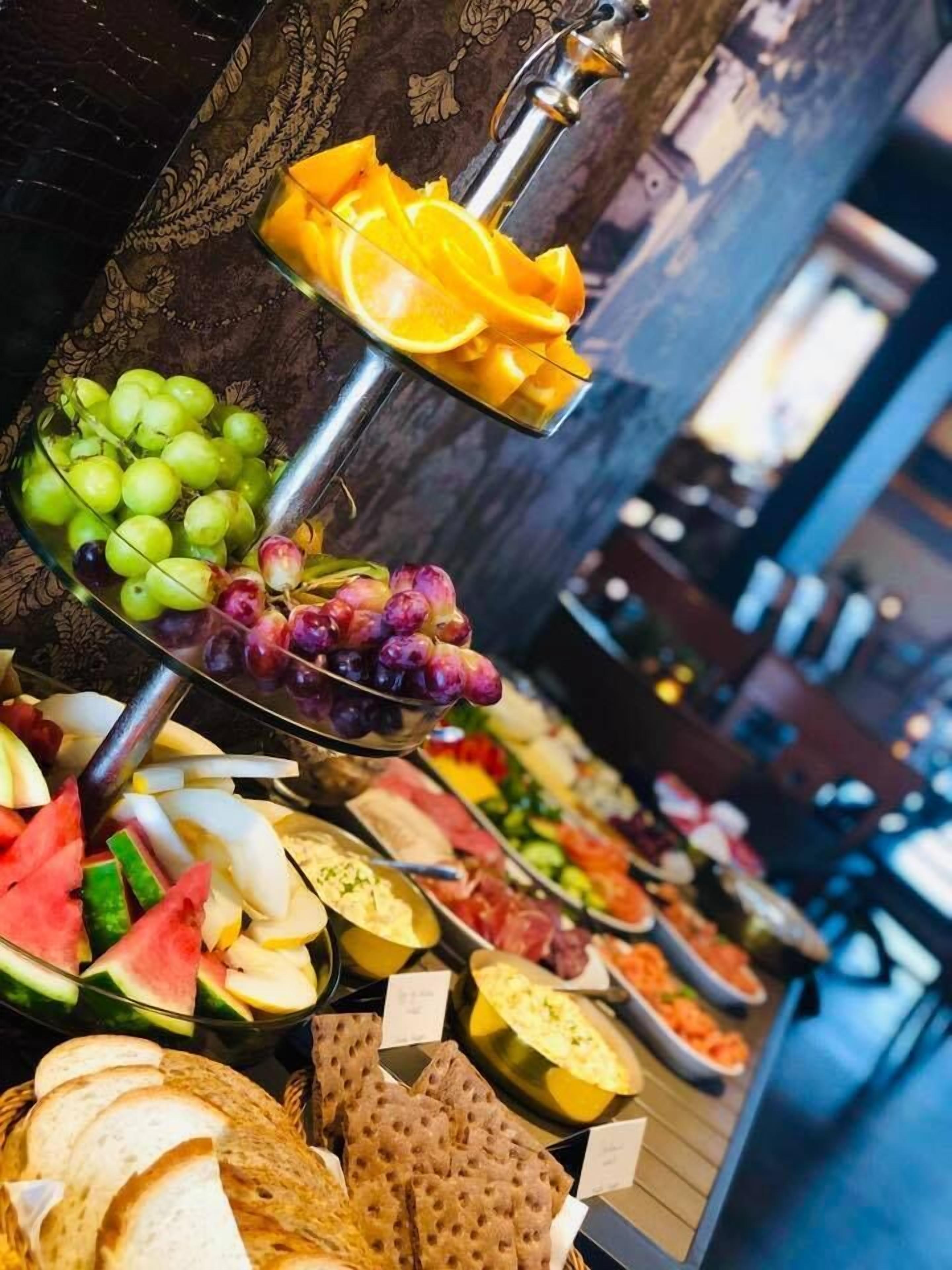 Ein Buffet mit verschiedenen Speisen, darunter Obst, Käse und Brot.