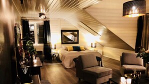 A cozy, well-lit room with a bed, two armchairs, a small table, and a mirror on the wall. - Veiholmen Brygge (Smøla)