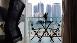A modern room with a view of high-rise buildings, a desk with a chair, and a small table with a plant. - Classic Studio in Kuala Lumpur 10 minutes to city center (Kuala Lumpur)