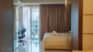 A modern hotel room with a bed, a desk, and a chair. There is a balcony with a view of buildings outside. - Classic Studio in Kuala Lumpur 10 minutes to city center (Kuala Lumpur)