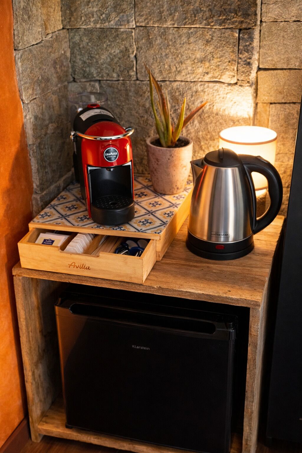 A compact kitchen setup with a coffee maker, a kettle, and a drawer organizer on a wooden surface.