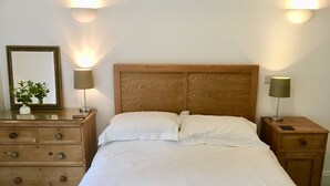 A bedroom with a wooden headboard, two bedside tables with lamps, a dresser, and a mirror. - Self Contained Stay, set within 7 acres of gated grounds, for 2 or 3 guests (Kingsfold)
