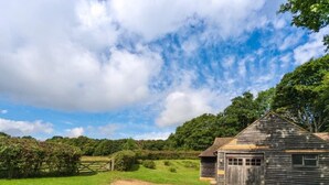 A rustic wooden building with a sloped roof, a single garage door, and a small window. - Self Contained Stay, set within 7 acres of gated grounds, for 2 or 3 guests (Kingsfold)