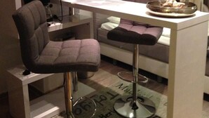 A modern kitchen with a bar stool, a dining table, and a sofa. - Art-Hüs (Sylt)