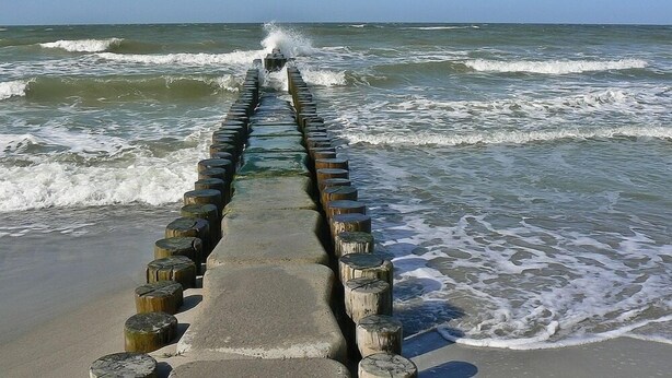 A concrete walkway with wooden posts leading to the ocean. - Art-Hüs (Sylt)