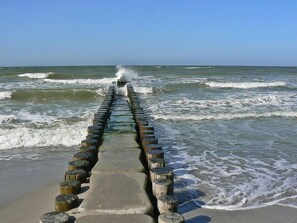 A concrete walkway with wooden posts leading to the ocean. - Art-Hüs (Sylt)