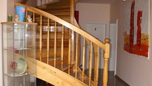 A wooden staircase with glass shelves on the left. - Art-Hüs (Sylt)