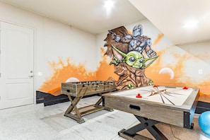A foosball table in a room with a mural of a character on the wall.