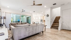 A modern living room with a sofa, a coffee table, and a ceiling fan. - EV_1472 - 5 Bed 5.5 Bath Villa with Screened-In Private Pool, Kids Room (Kissimmee)