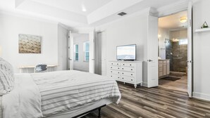 A bedroom with a bed, a dresser, a television, and a bathroom visible through an open door. - EV_1472 - 5 Bed 5.5 Bath Villa with Screened-In Private Pool, Kids Room (Kissimmee)