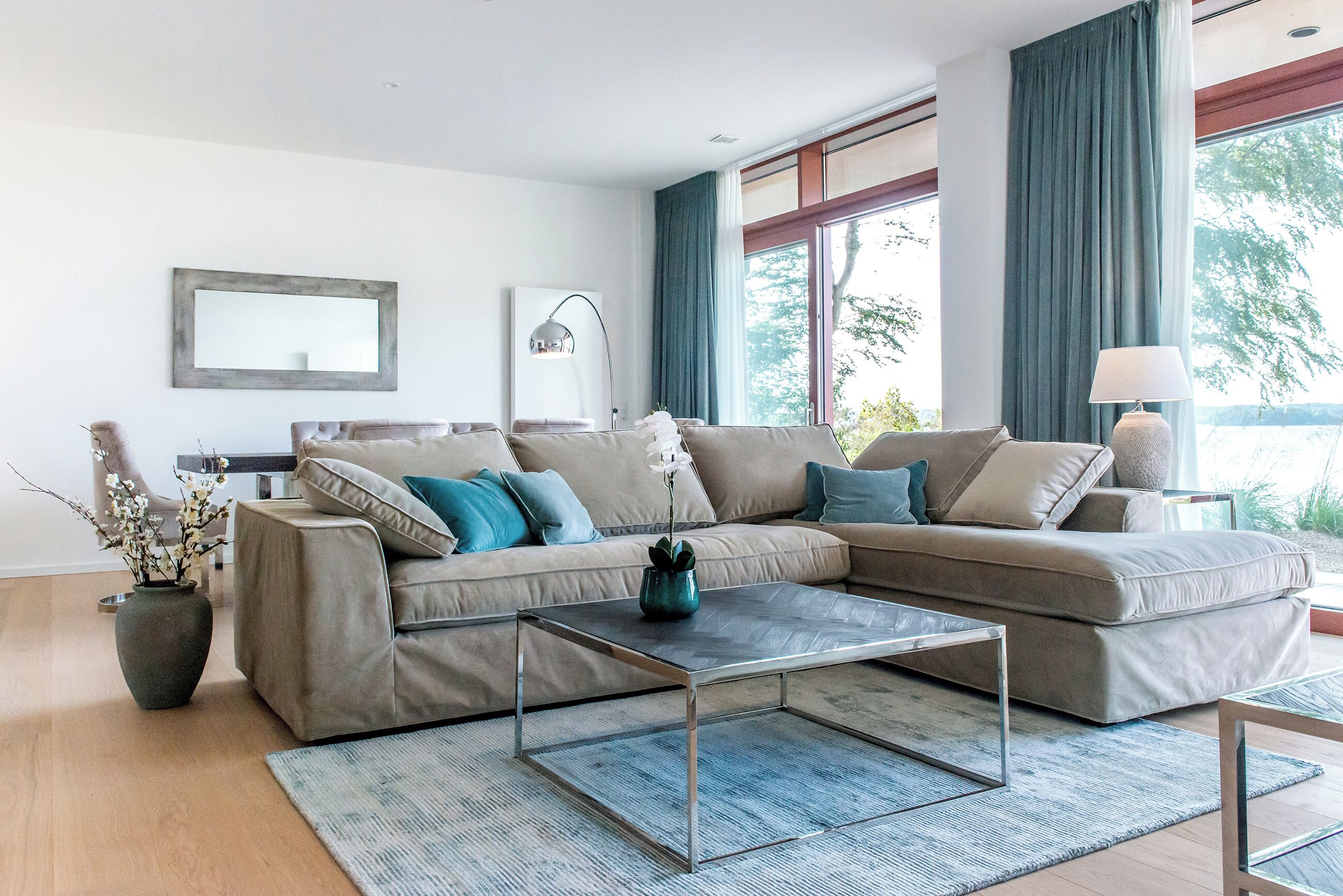 A modern living room with a sectional sofa, a coffee table, and a vase with flowers.