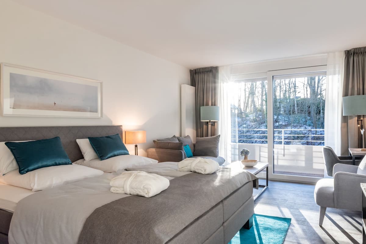 Ein Hotelzimmer mit einem großen Bett, einer Couch, einem Schreibtisch und Blick auf eine verschneite Landschaft durch die Fenster.