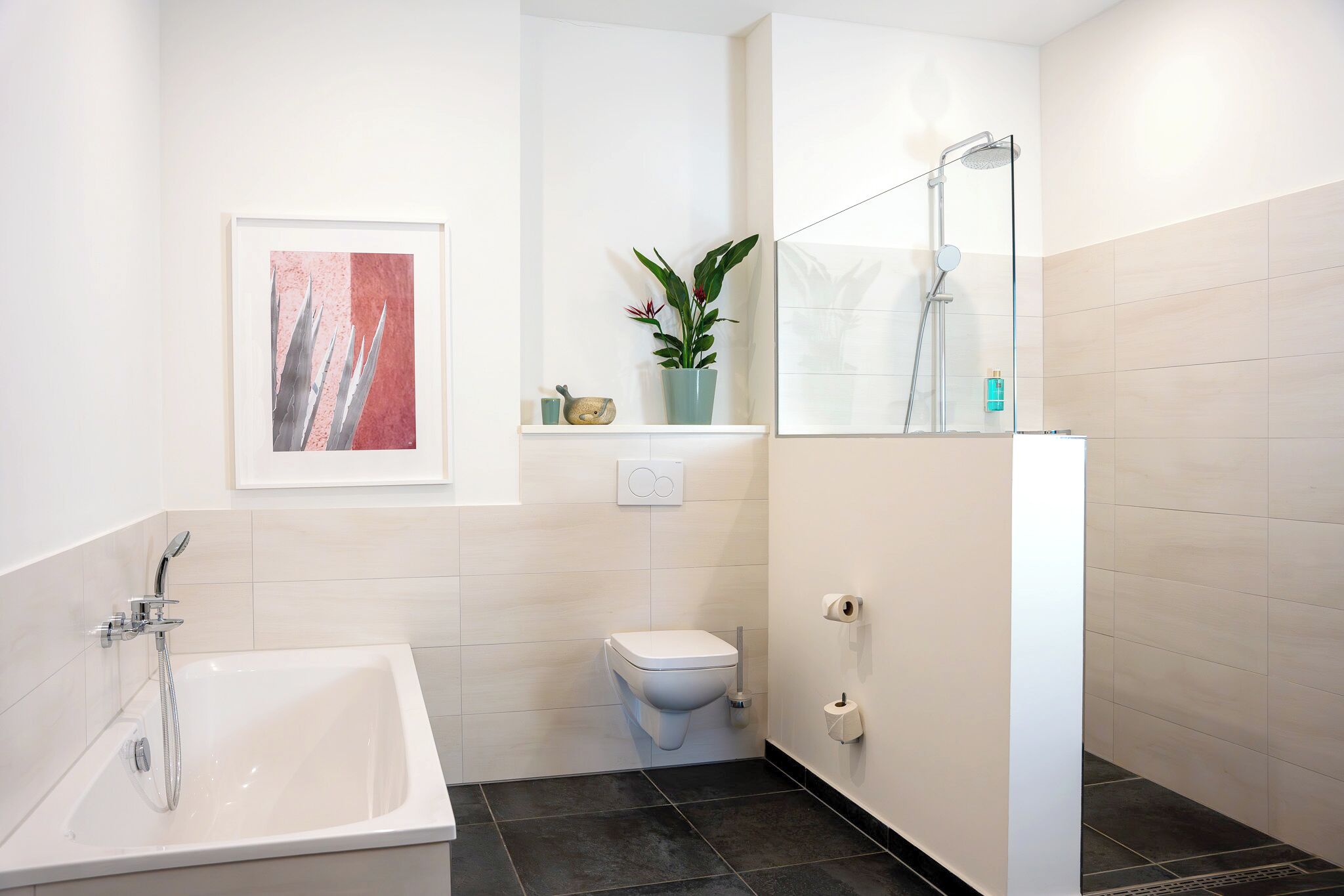 A modern bathroom with a bathtub, toilet, and shower.