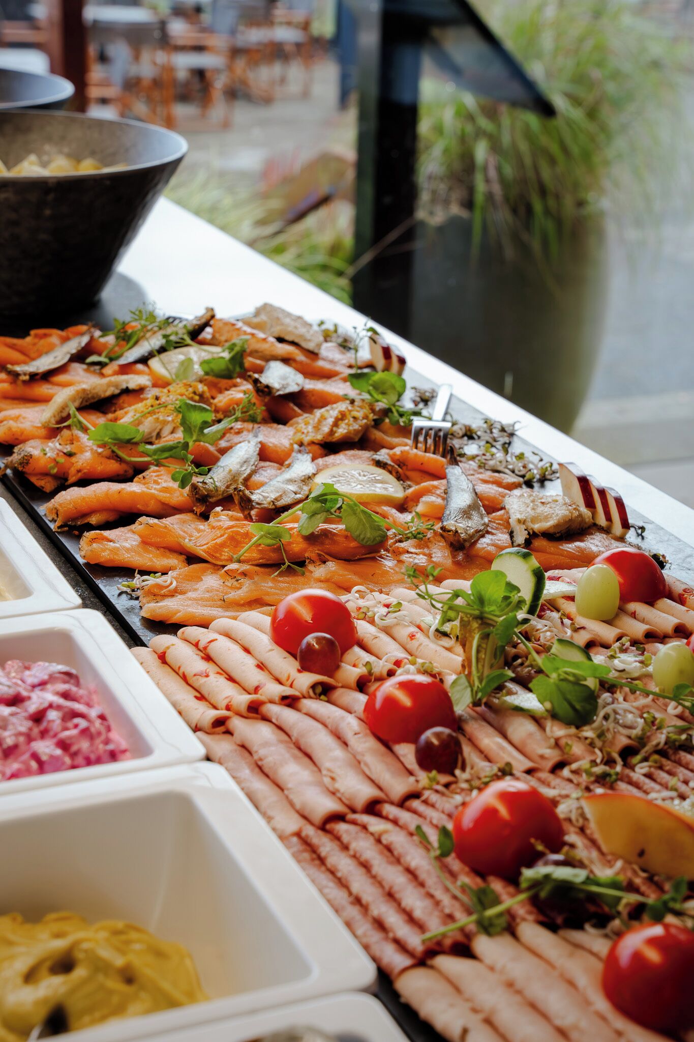 Buffet com diversos alimentos, incluindo salmão, vegetais e carnes.