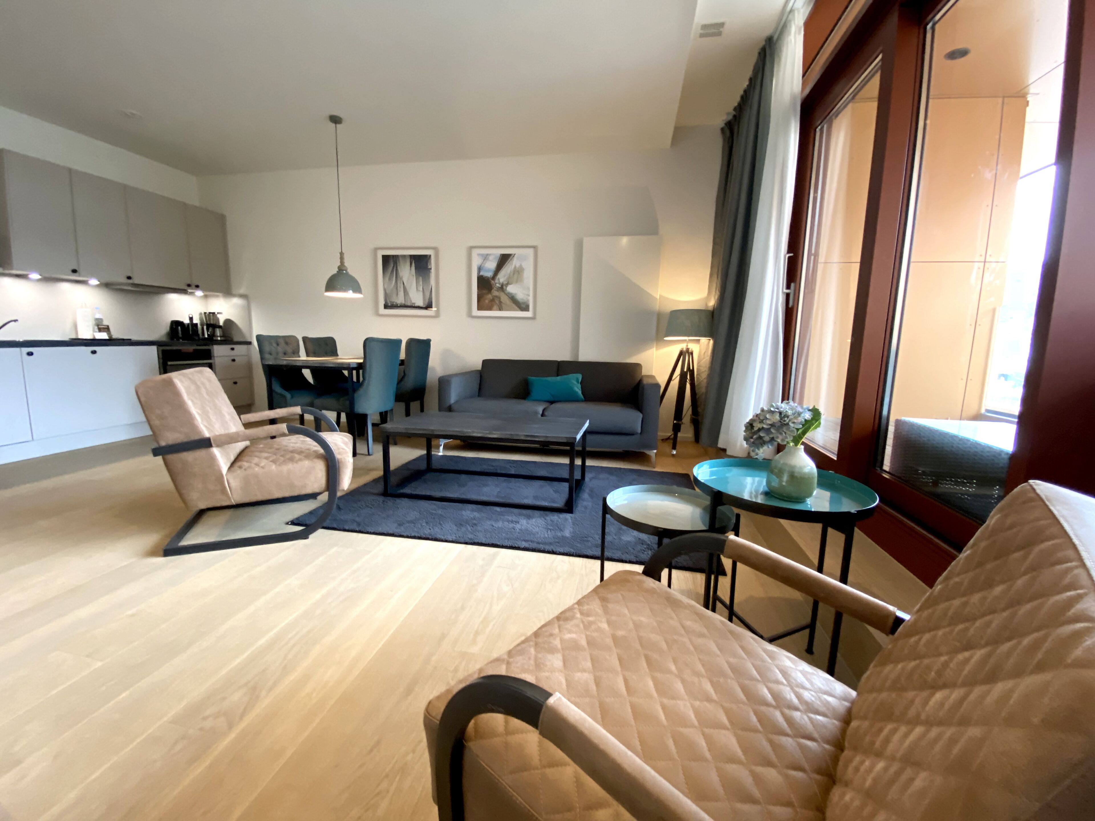 Un salon moderne comprenant un canapé, des fauteuils, une table basse et un coin repas avec des chaises et une table.