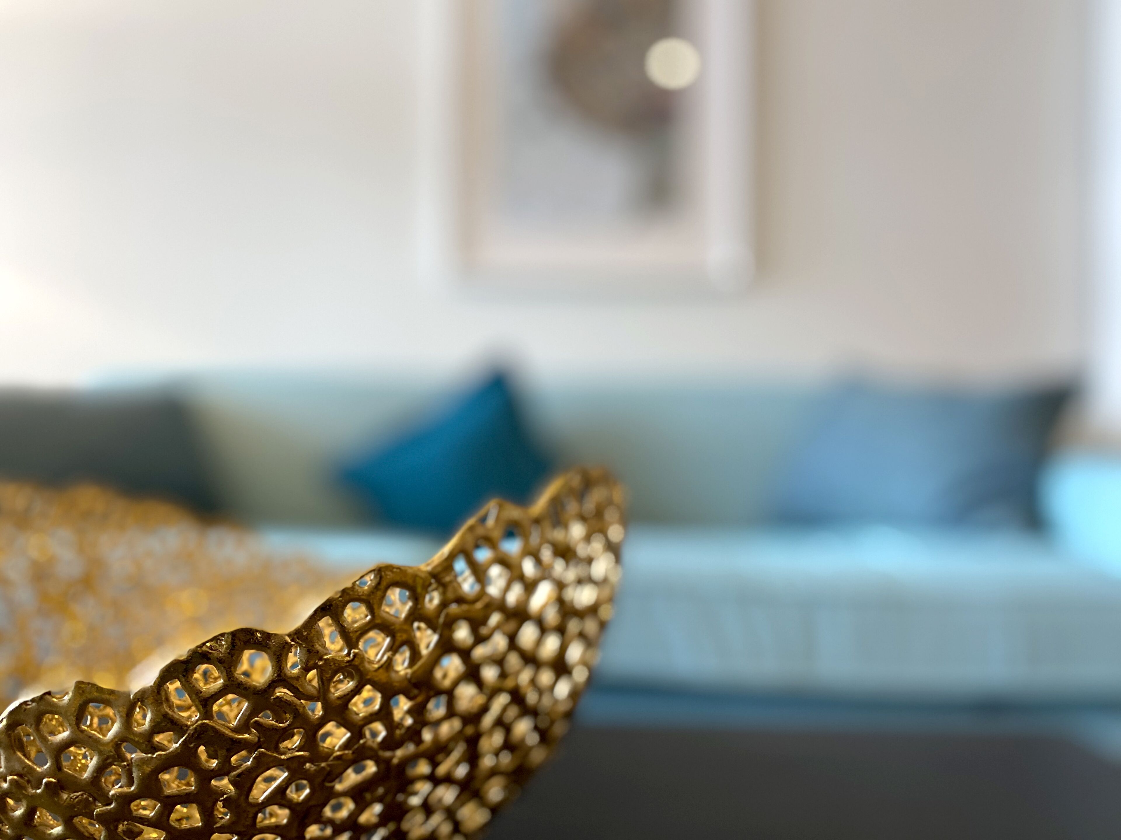 A close-up of a gold decorative item with a geometric pattern, placed on a dark surface.