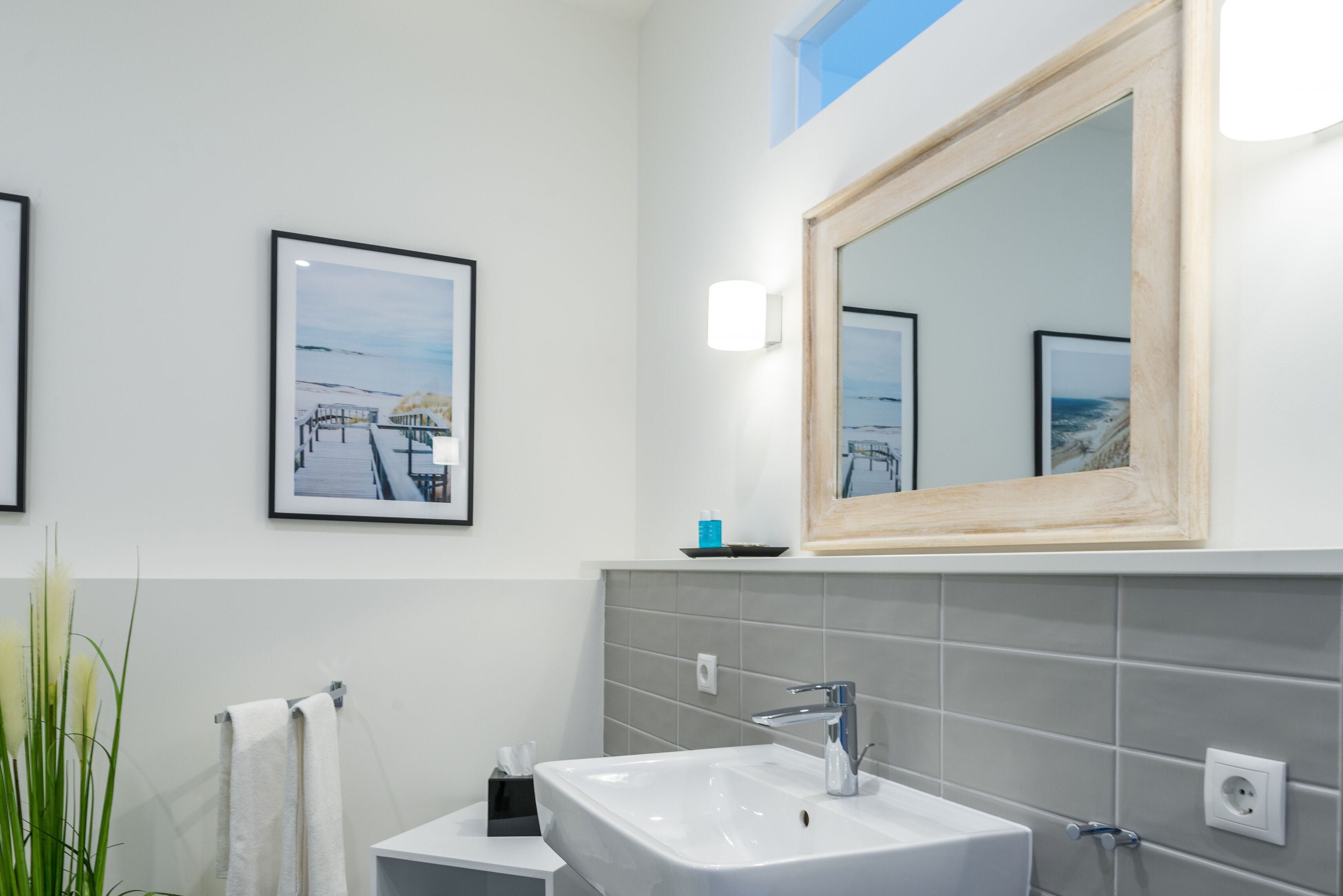 A modern bathroom with a large mirror, a white sink, and a towel rack.