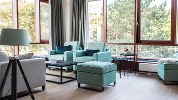 A modern living room with large windows, a tripod, and a table with a bowl.