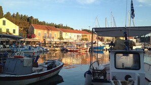 Un port de plaisance avec des bateaux amarrés, un bâtiment avec un toit rouge et un ciel dégagé.