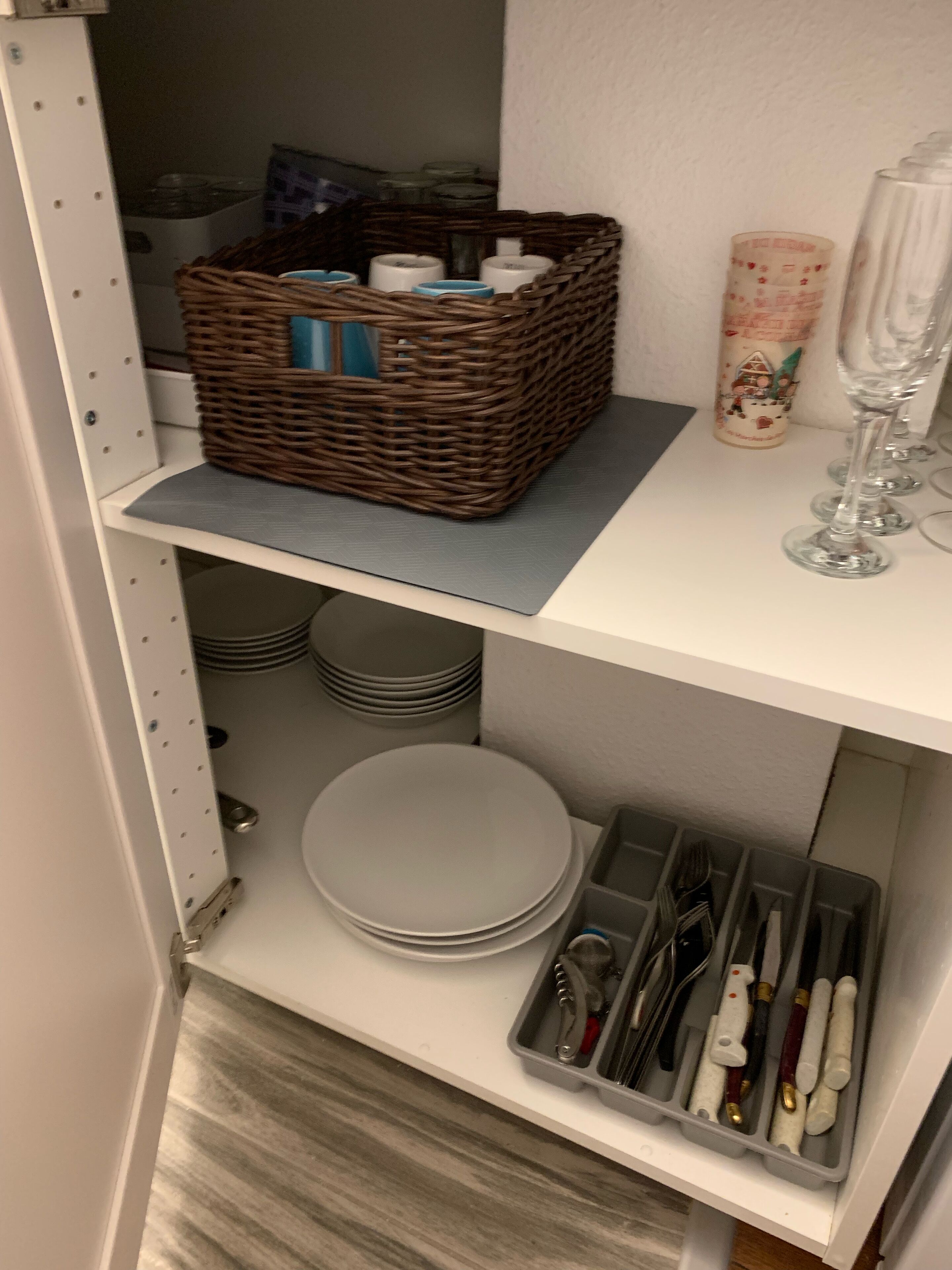 Ein Lagerraum mit Regalen, auf denen ein Korbwäscher, Glaswaren, Teller und Besteck stehen.