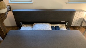 Una cama con cabecera gris y un banco gris en frente.