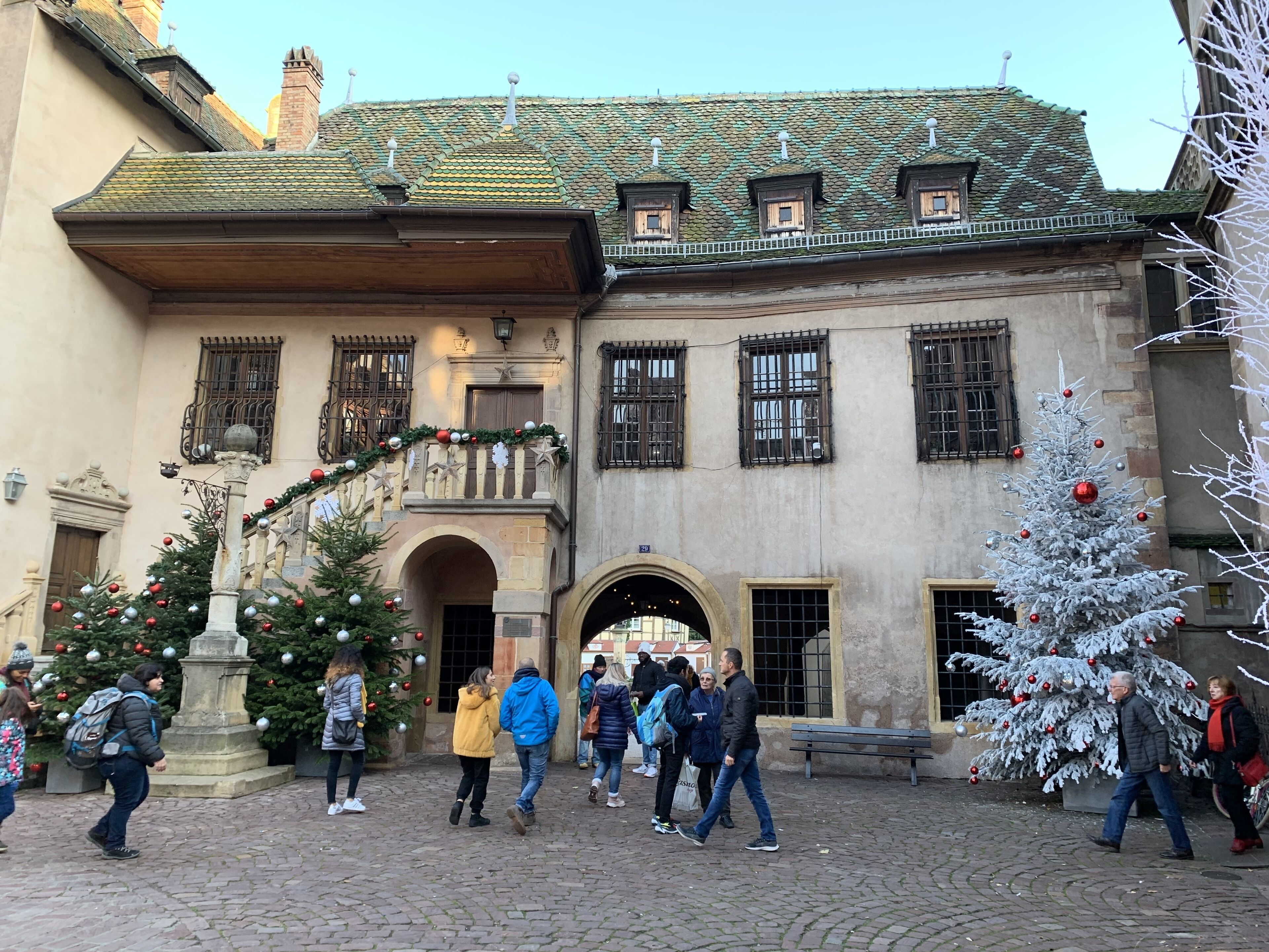 Ein historisches Gebäude mit einem Kopfsteinpflasterhof, verzierten Balkonen und einem zentralen Eingang.
