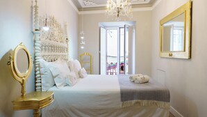 Un dormitorio con una cama grande, un candelabro, un espejo y vistas al exterior.