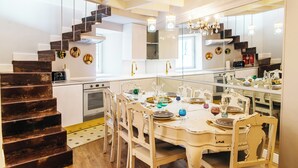 Una cocina con una mesa de comedor preparada para seis personas, una escalera y un espejo grande que refleja la cocina.