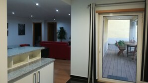 Una cocina moderna con encimeras de granito, un sofá rojo y una zona de comedor con mesa y sillas.