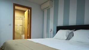 Una habitación de hotel con una cama, una puerta que da al baño y un aire acondicionado de pared.