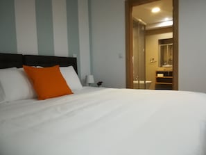 A hotel room with a large bed, a nightstand, a lamp, and a bathroom visible through an open door. - Lisbon Grand View (Lisbon)