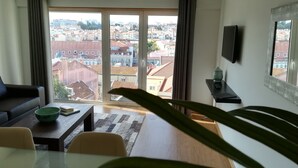 Una sala de estar moderna con un amplio ventanal corredera que da a una vista de la ciudad.
