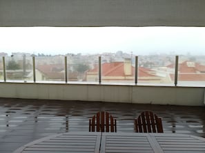 A covered outdoor seating area with a view of a cityscape through a window. - Lisbon Grand View (Lisbon)