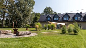 A house with a sloped roof, multiple windows, and a well-maintained lawn with various plants and a stone pathway.